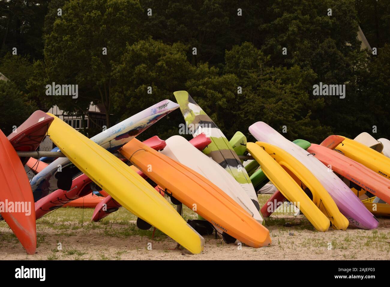 A group of kayak, rowboats and stand up paddleboards lined up on a rack at a rocky beach. Stock Photo