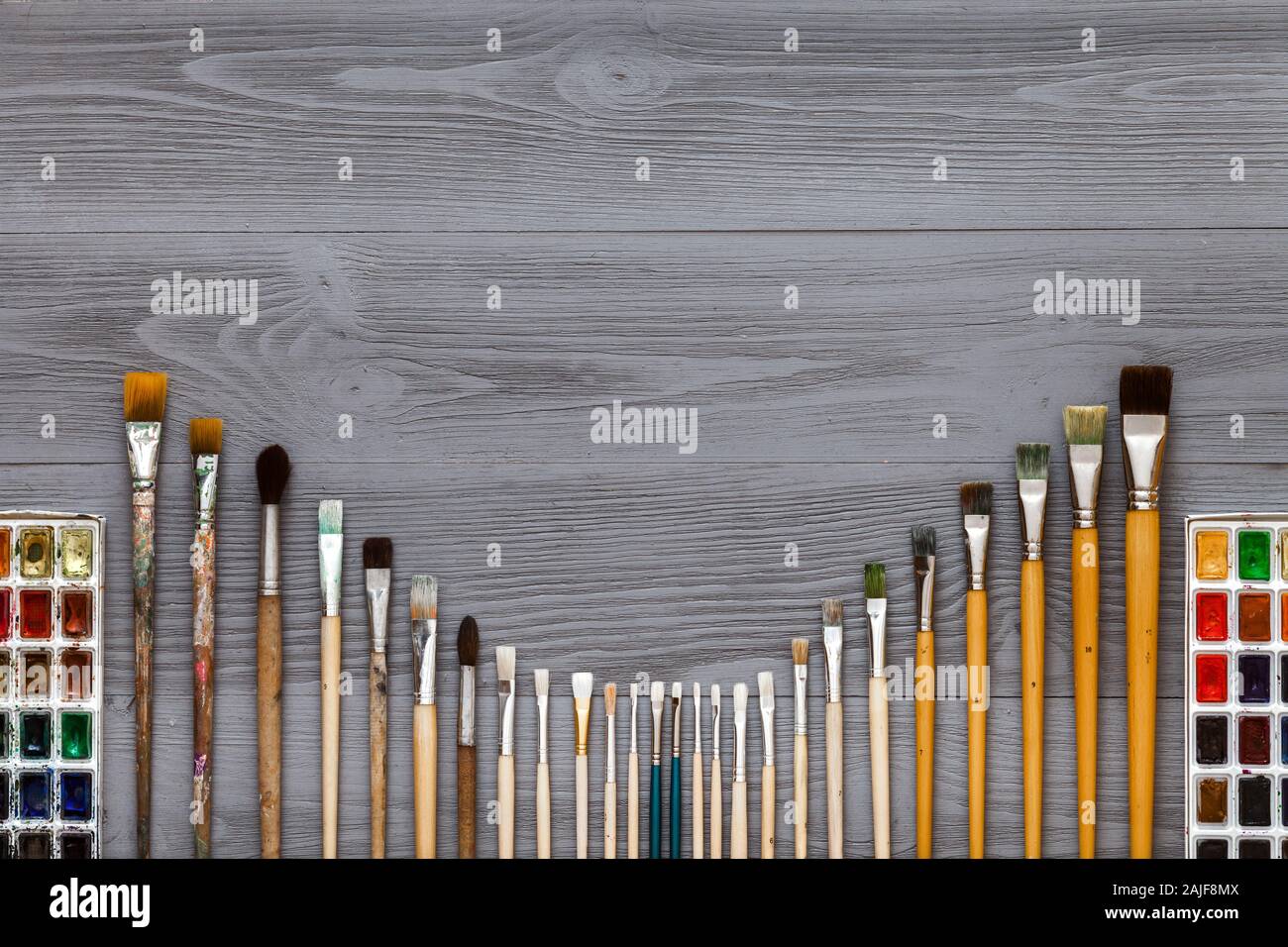 Paintbrushes set and watercolor paints on grey wooden table Stock Photo