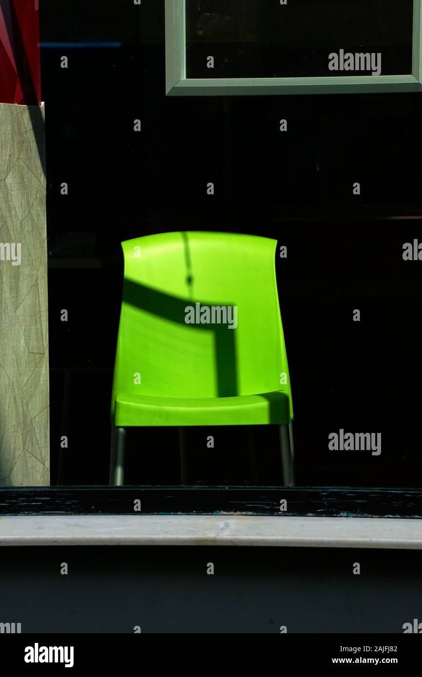 Abstract composition with a green plastic chair and geometric shapes , light and shadows. Concept image. Stock Photo