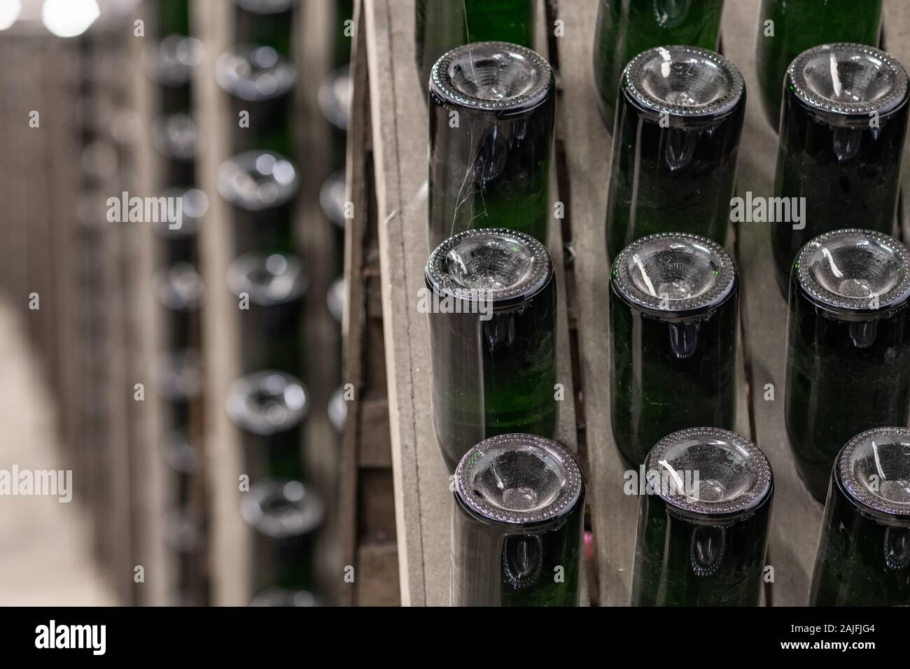 Sparkling wine bottles stacked up in old wine cellar close-up background.  Stock Photo