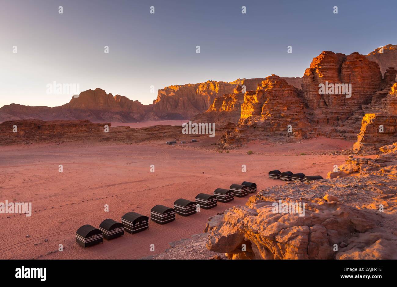 Wadi Rum desert, Jordan. Beautiful aerial view of bedouin camp at sunset from above with tents lined up and red rock formations. Panoramic landscape Stock Photo