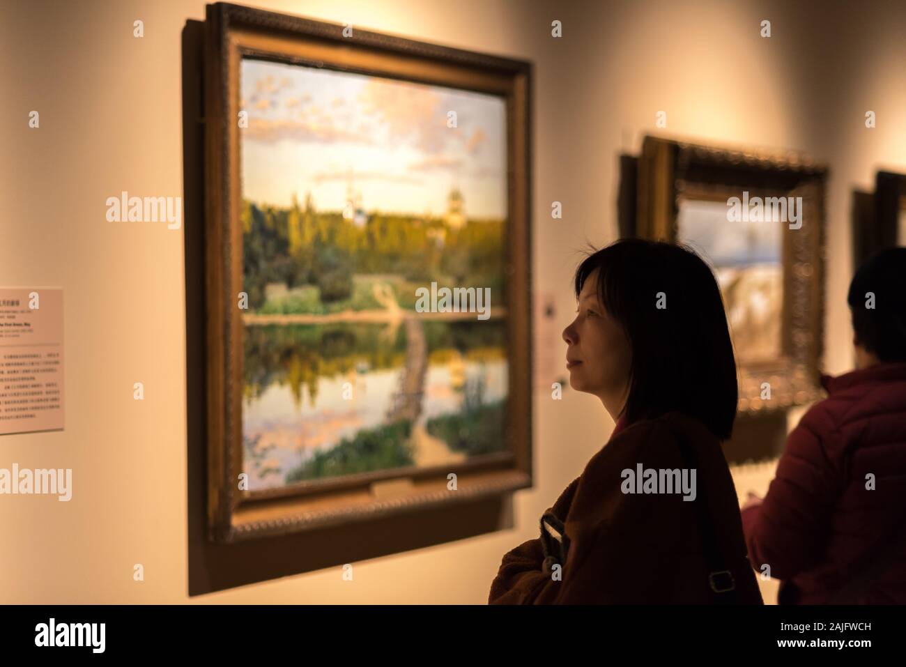 Shanghai, China: Asian woman, museum visitor looking at a framed painting on display, art exhibition at Shanghai Museum Stock Photo