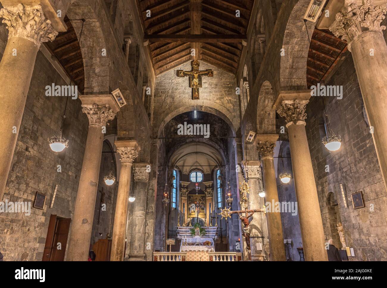 Genoa, Genova, Italy: Interior of romanesque church Chiesa di San Donato: stone walls, wooden roofing (trusses), wooden crucified Jesus (crucifix) Stock Photo