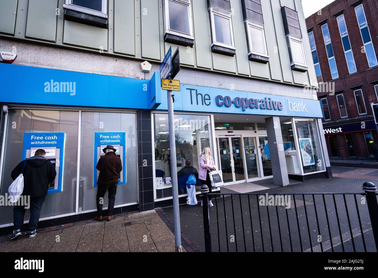 People, customers using the ATM, Cash machines at the Co-operative bank on the high street in the city centre, withdrawing money Stock Photo