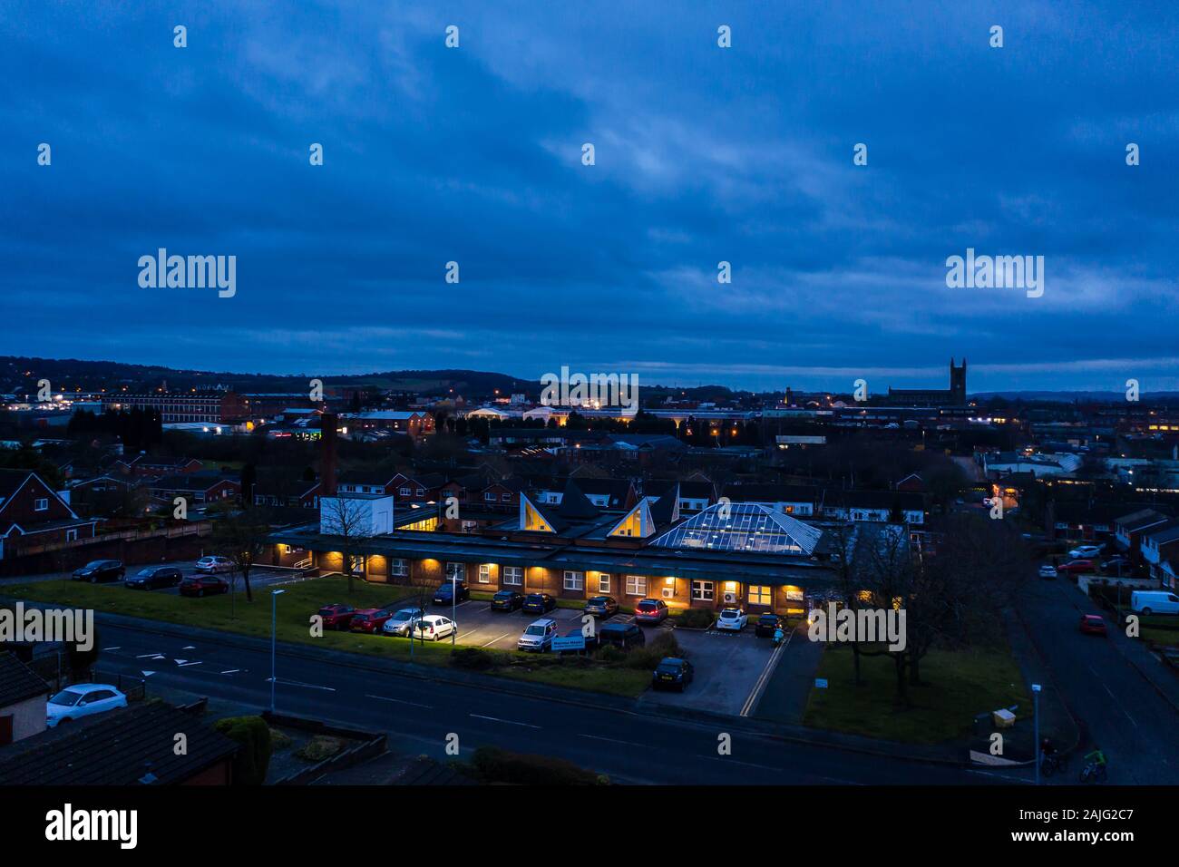 The sun goes down over the city as street lights light one of the middle class areas of the city, Longton health centre, NHS Stock Photo