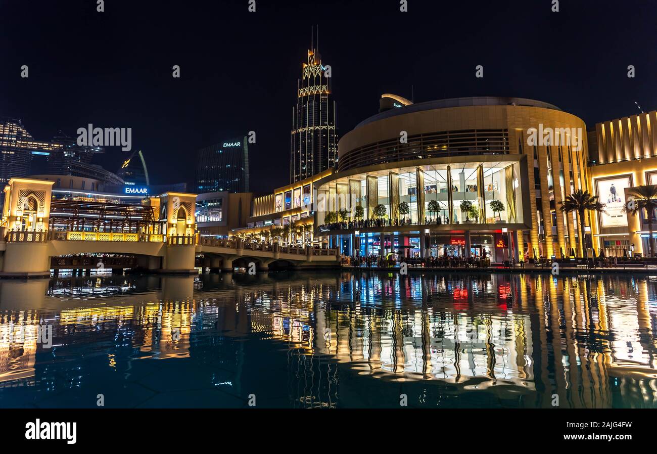 Dubai, United Arab Emirates: Exterior of Dubai Mall by night opposite Burj Khalifa tower, illuminated shop windows, luxury fashion brands Stock Photo