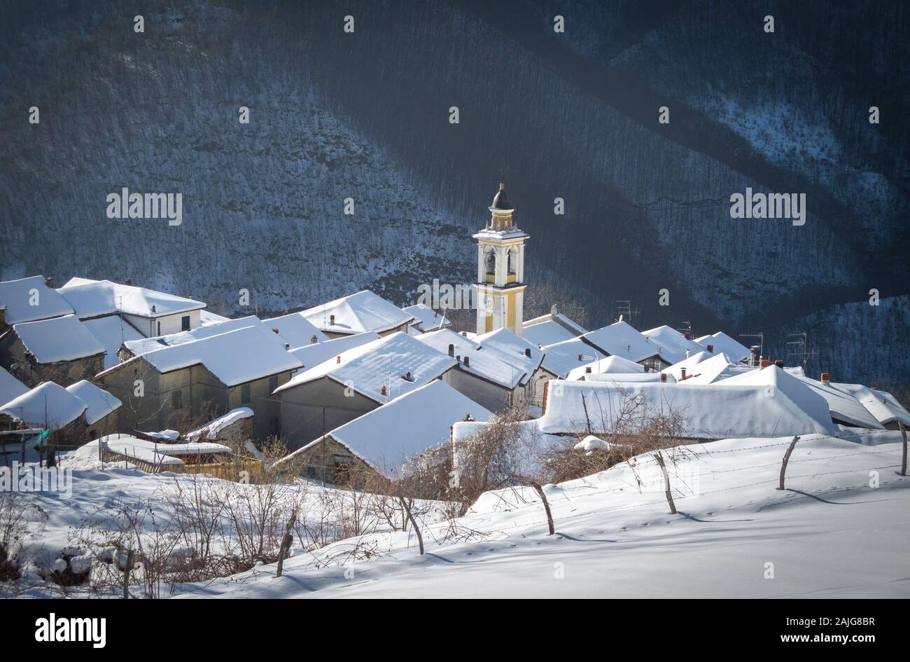 Bertone (Ottone), Piacenza, Italy: Scenic winter view of snow covered picturesque quaint Italian village, church bell tower and fresh snow on rooftops Stock Photo