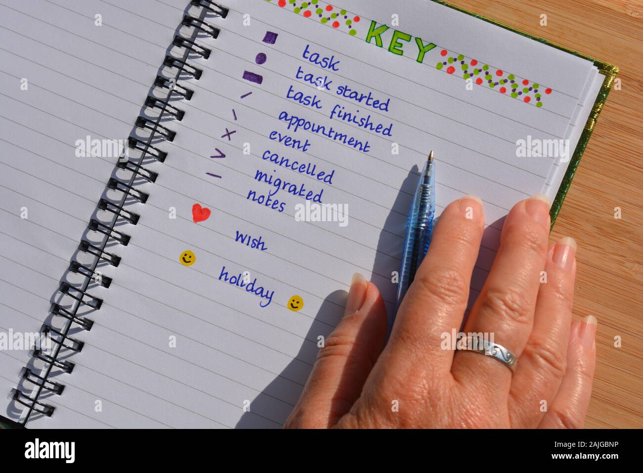 Woman writing in a bullet journal, pen in hand Stock Photo