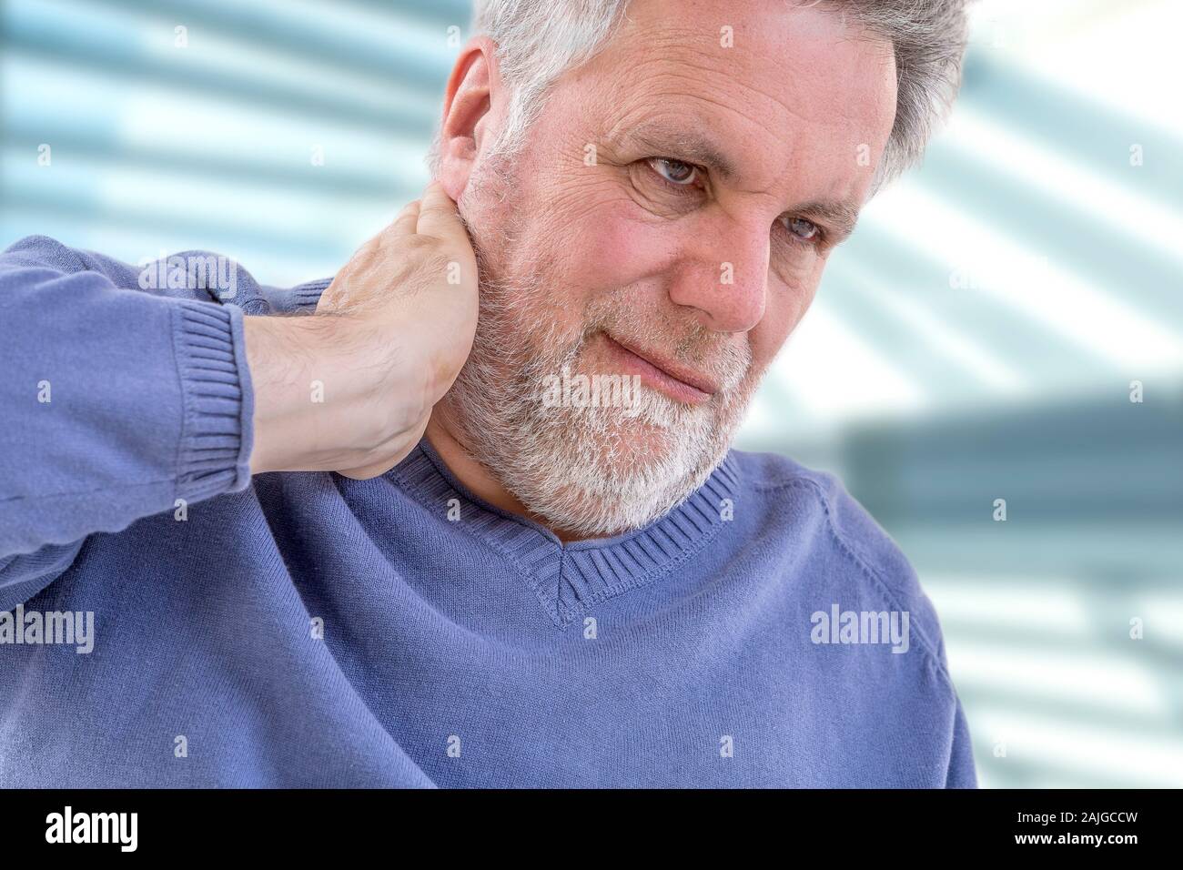 Senior man with a strong pain in the back of his neck front view Stock Photo