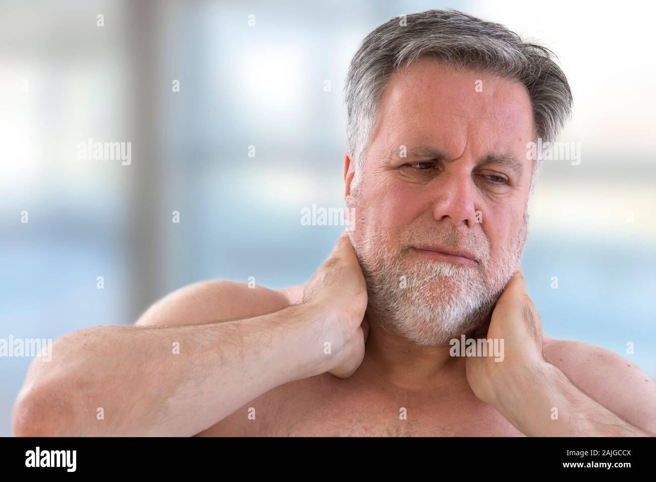 Senior man with a strong pain in the back of his neck front view Stock Photo
