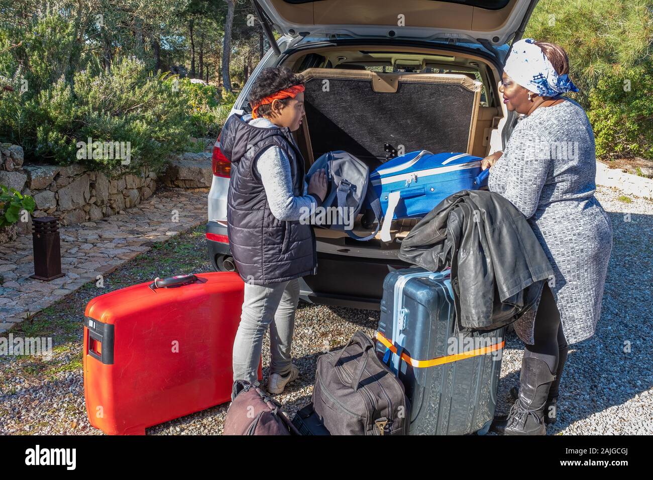 Woman loading suitcases in the car, with her son, a lot of baggage Stock Photo
