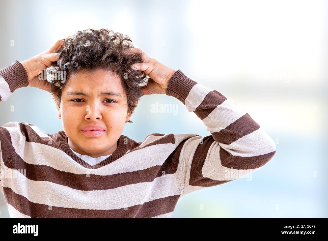 Stress boy scratching his hair with confused expression Stock Photo