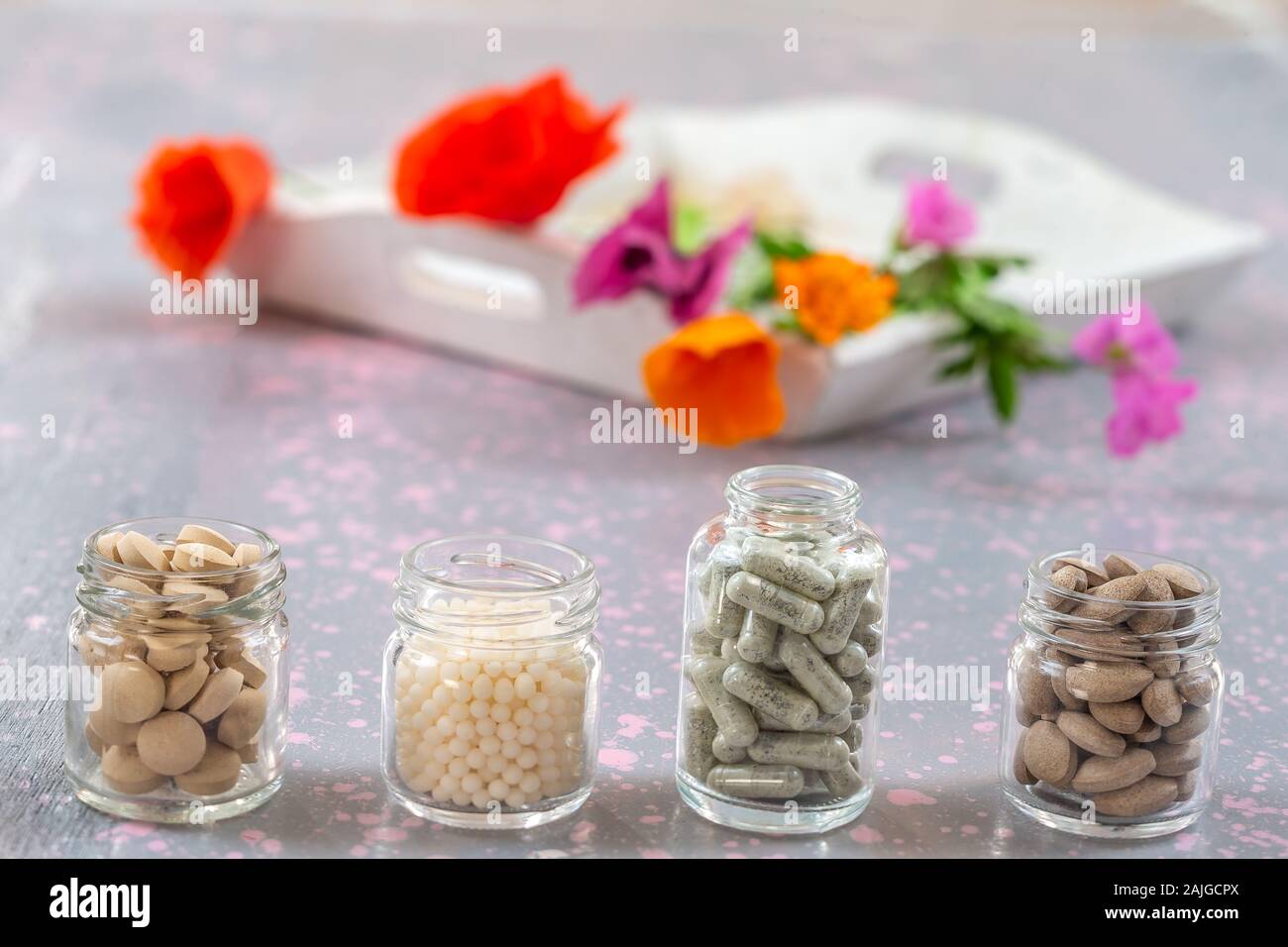 Herbal supplements and vitamins on wooden tray , decorated with colorfull medicinal flowers and herbs blurry wooden background Stock Photo