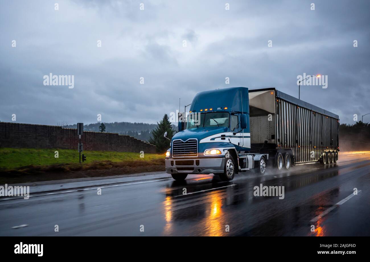 Big rig day cab blue semi truck with roof spoiler transporting