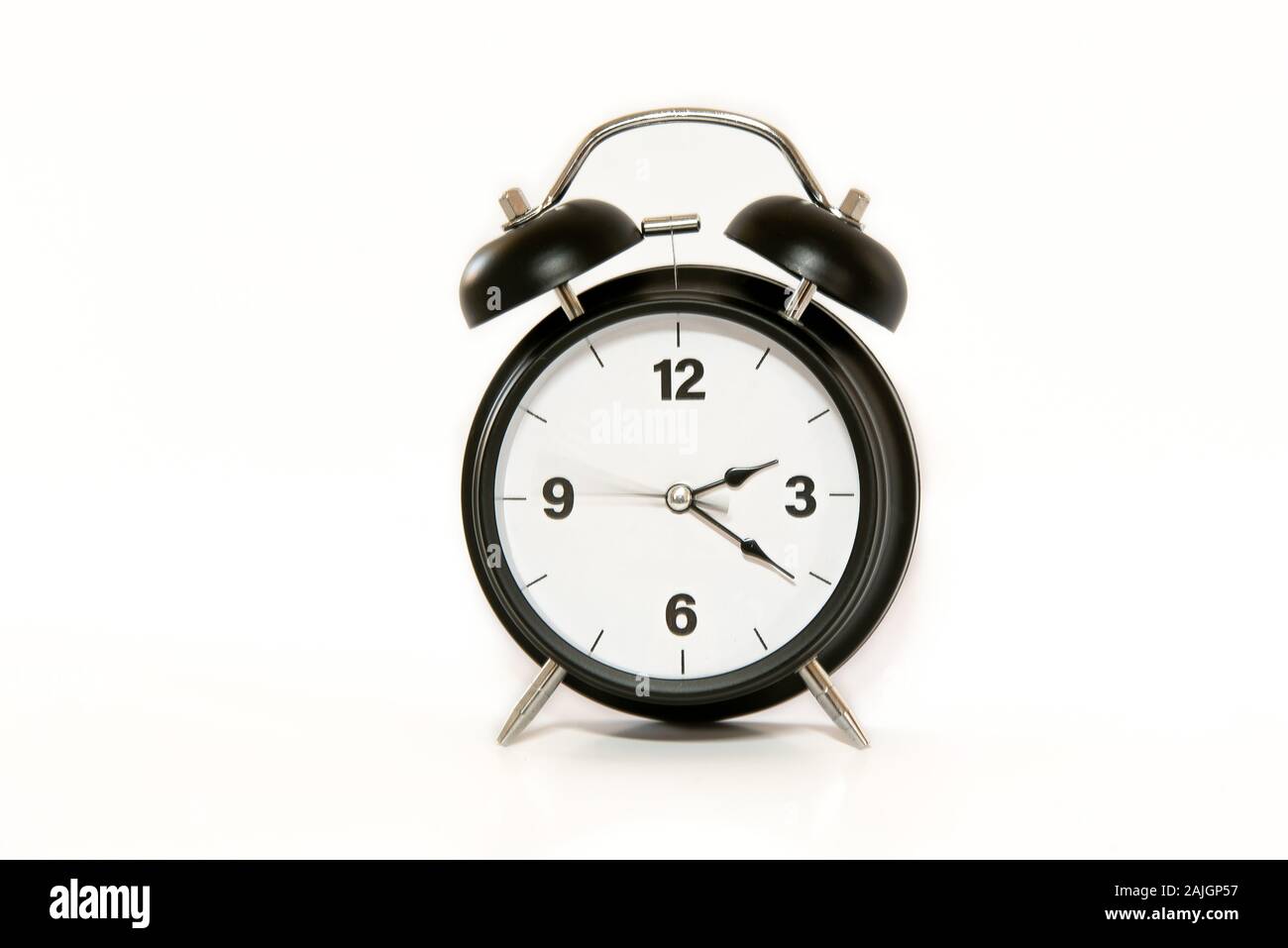 Vintage alarm clock with simple and minimalist design, isolated on white background. Second arm in movement, feeling of passing time, ticking. Stock Photo