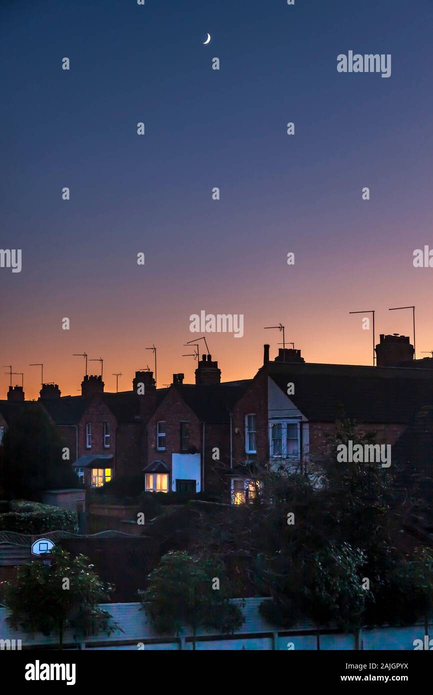 Northampton, UK. Colourful sky just after sunset over the rooftops of the Abington Area of town a fading quarter moon high in the sky. Stock Photo