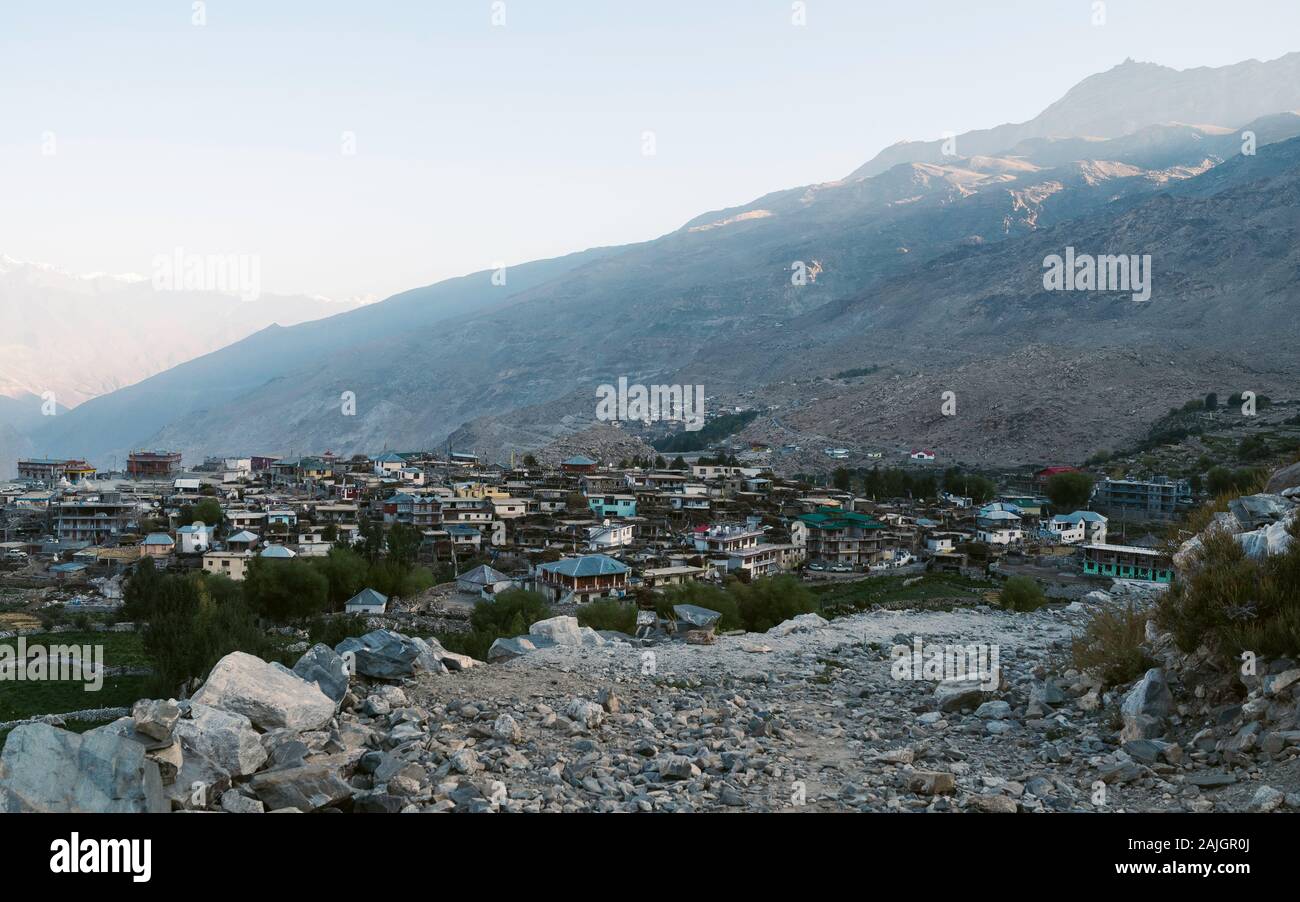 Nako village flanked by fields, high Himalayan mountains, and rocky footpath in the Spiti valley at sunrise in Himachal Pradesh, India. Stock Photo