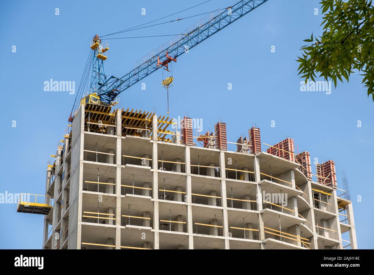 Concrete frame of tall apartment building under construction and tower ...