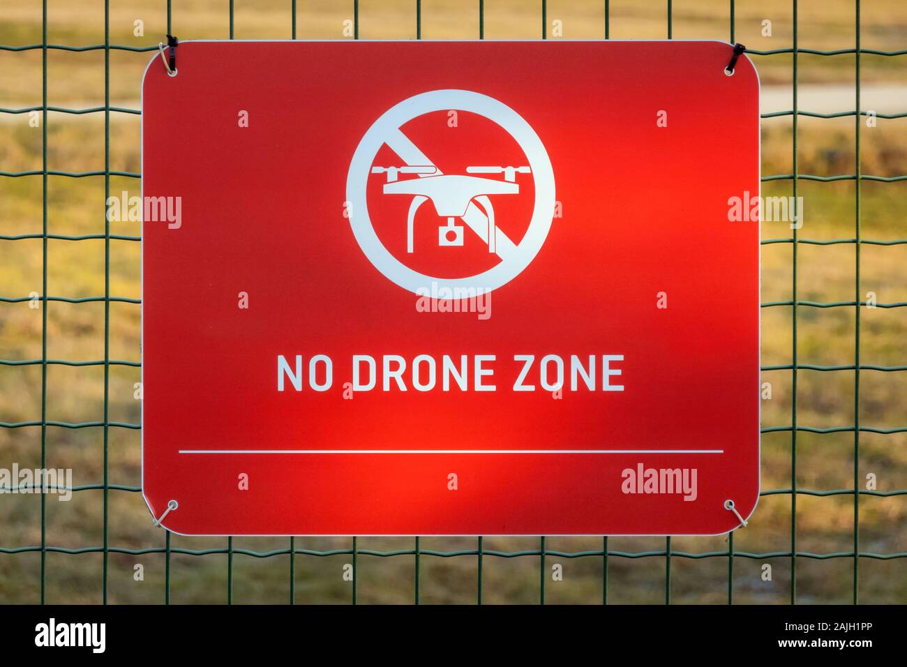 Red no drone zone sign on the fence. Restricted flight area symbol hanging in airport. Prohibited done flying place Stock Photo