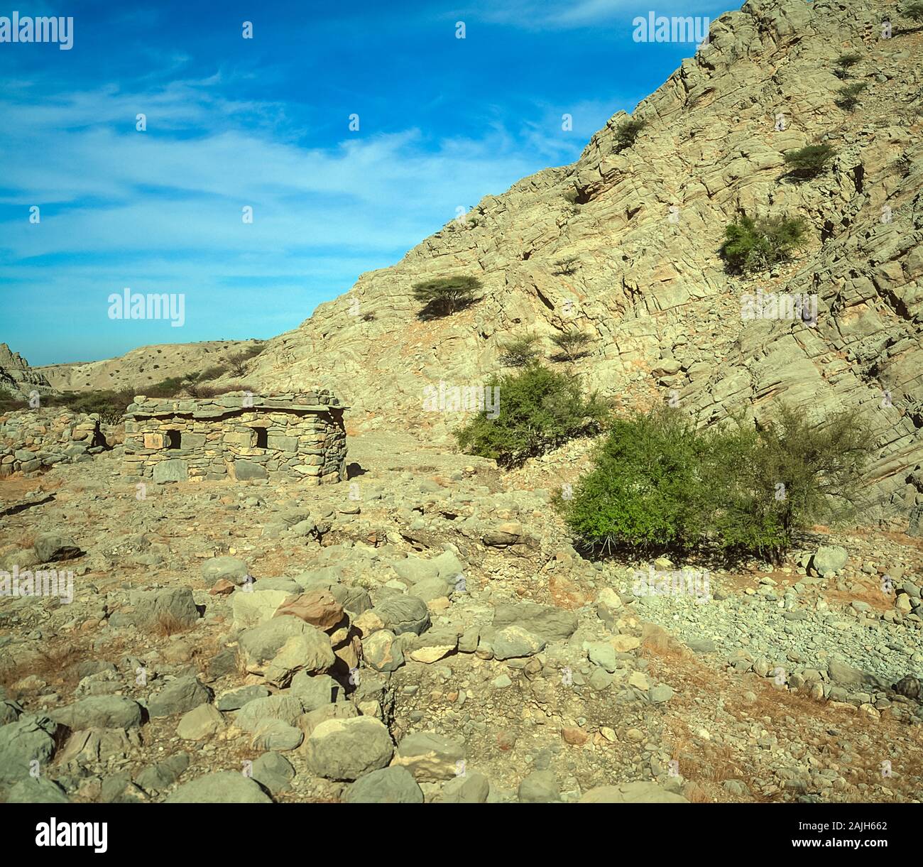 Abandoned summer house in the rugged scenery of the Al Hajr and Musandan mountains of the Arabian Peninsula shared by the Emirates of Dubai, Ras Al Khaimah and Fujairah, seen here in Springtime Stock Photo