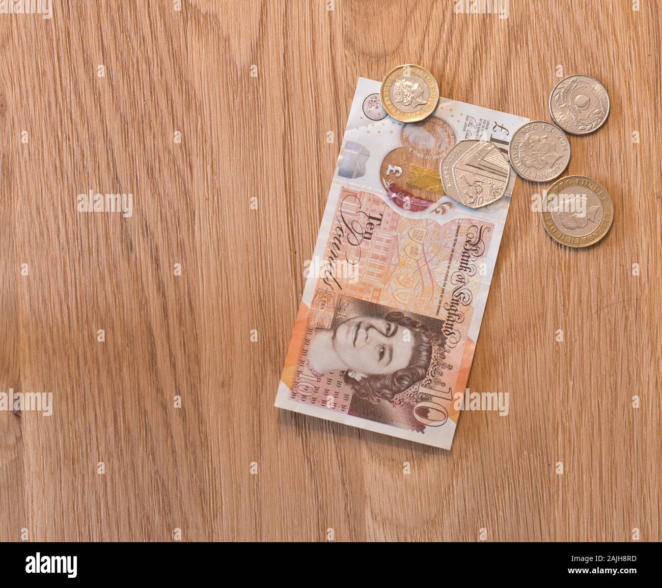 British currency notes and coins placed on a wooden background Stock Photo