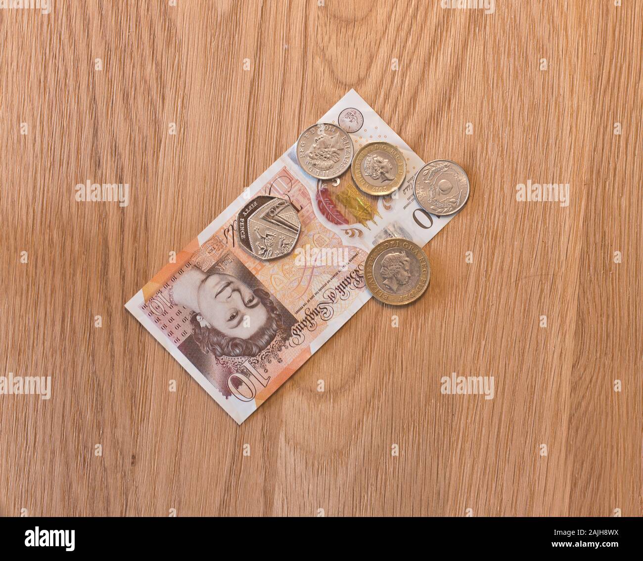 British currency notes and coins placed on a wooden background Stock Photo