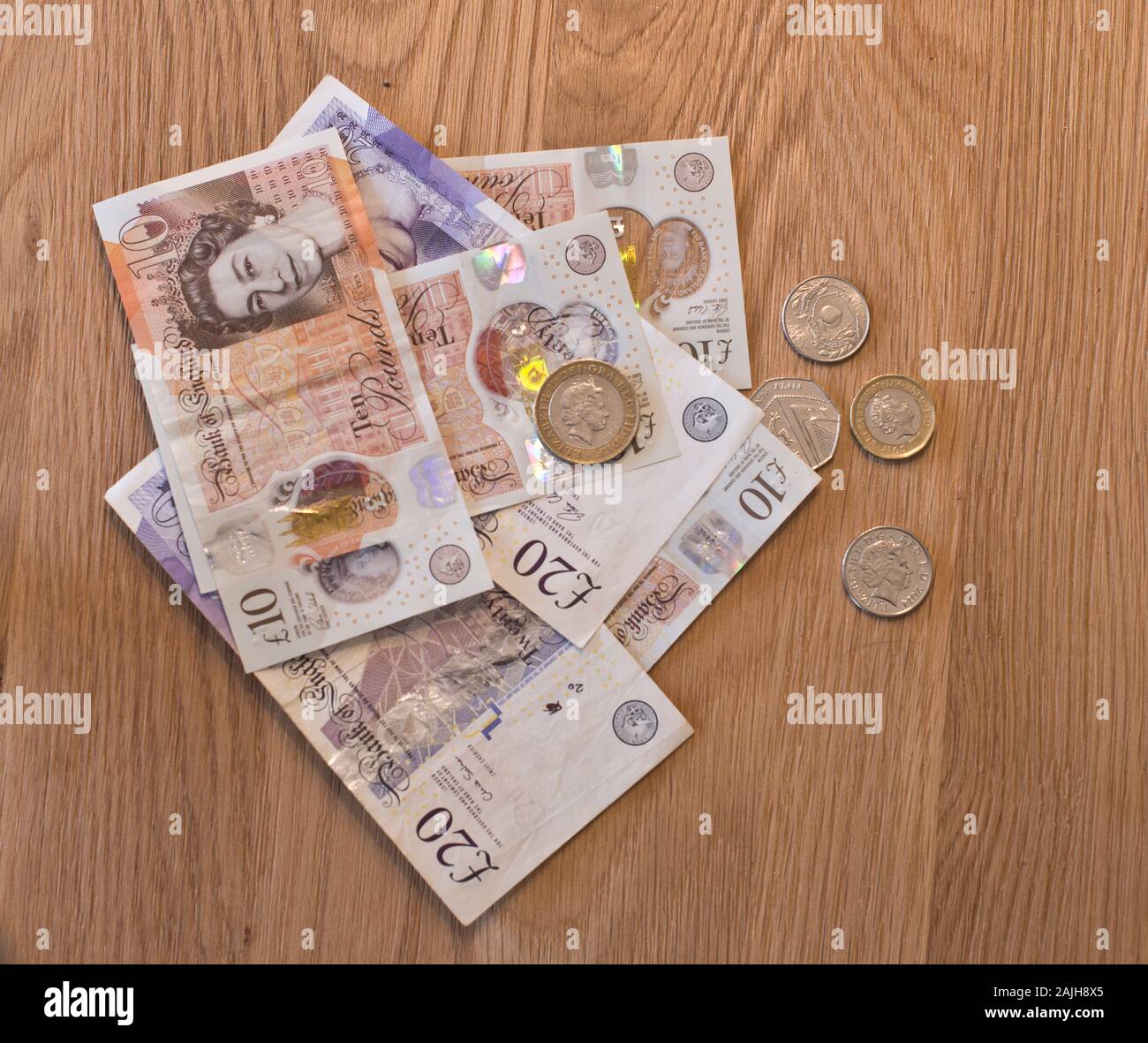 British currency notes and coins placed on a wooden background Stock Photo