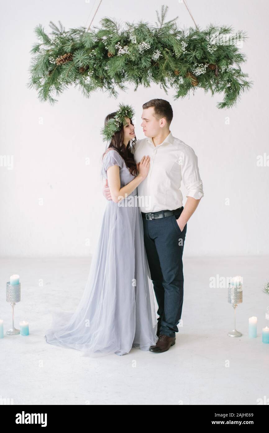 Bridesmaid and groomsmen studio portrait. Funny wedding moment. Portrait of  lovely couple on white wall background and pine and candle decoration Stock  Photo - Alamy