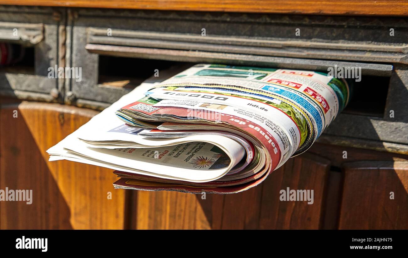 Junk mail flyers jammed into a mail slot of an old wooden door, adding to environmental concerns about our wasteful society Stock Photo