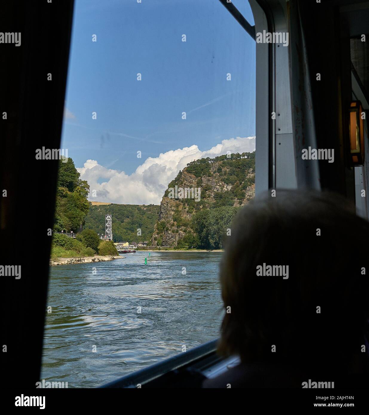 Woman peers out her KD Cruise Line Rhine River ship at the famous Lorelei Rock, in the World Unesco section of the Middle Rhine in Germany Stock Photo