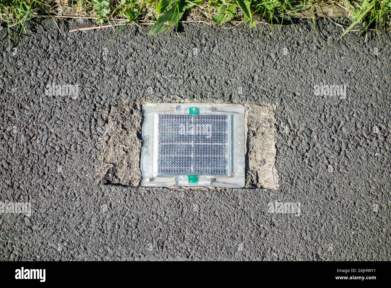 Small solar powered light set in a tarmac footpath in the UK Stock Photo