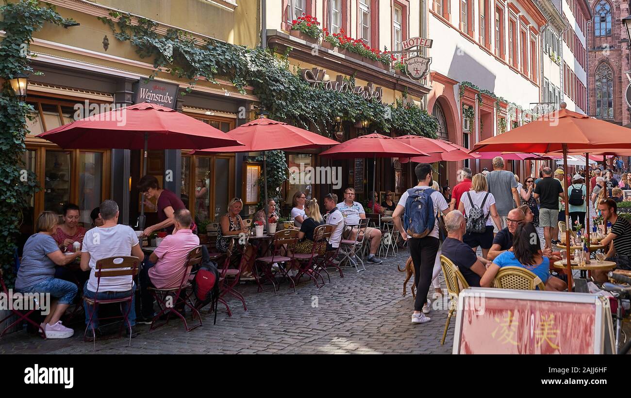 Cobblestone narrow street in Heidelberg Germany with tourists and people eating at outdoor