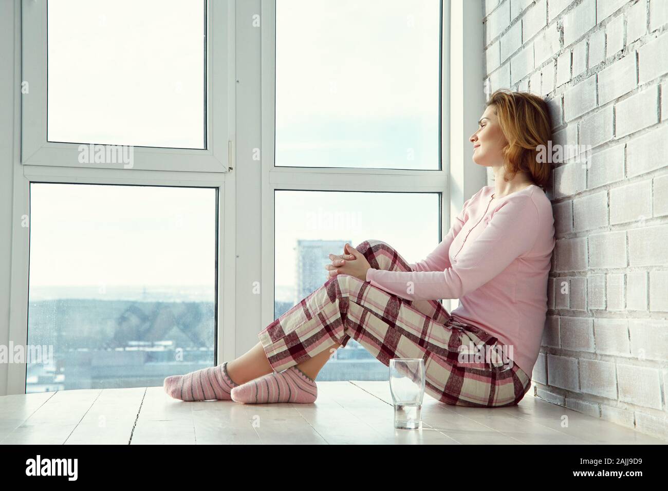 relaxed woman sitting on a floor near a window Stock Photo - Alamy