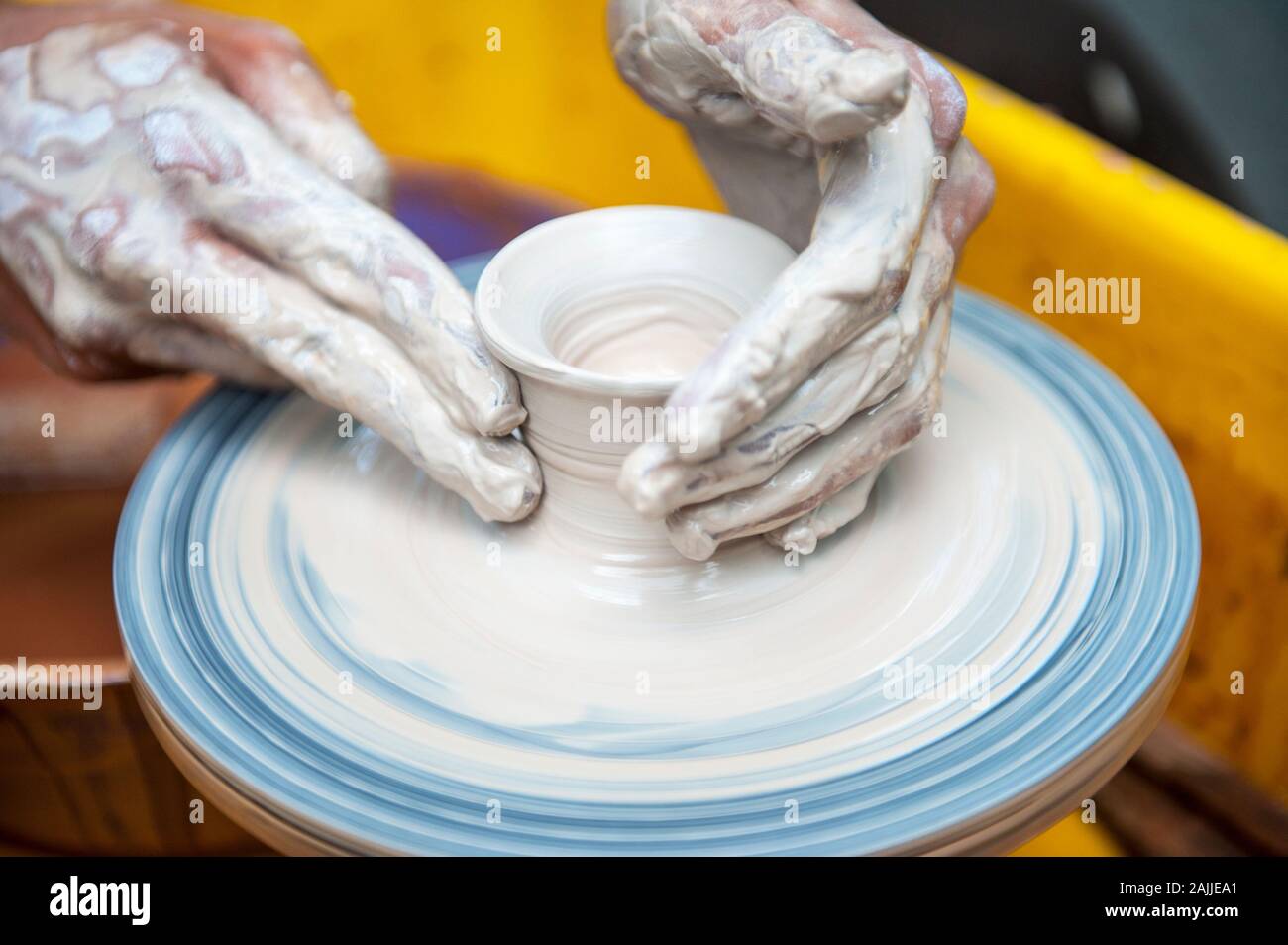 The potter makes pottery dishes on potter's wheel. The sculptor in