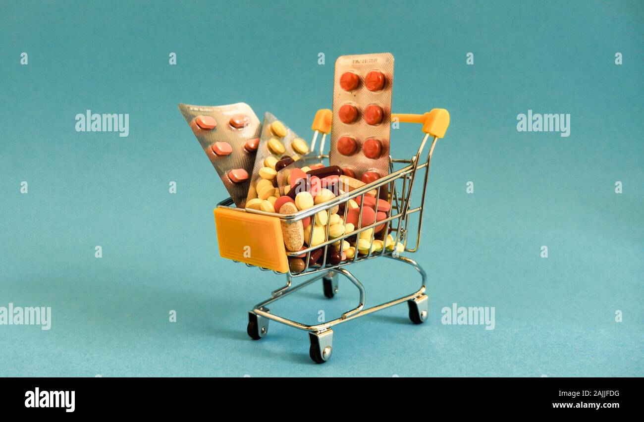 Supermarket trolleys filled with medical capsules on a coloured background Stock Photo
