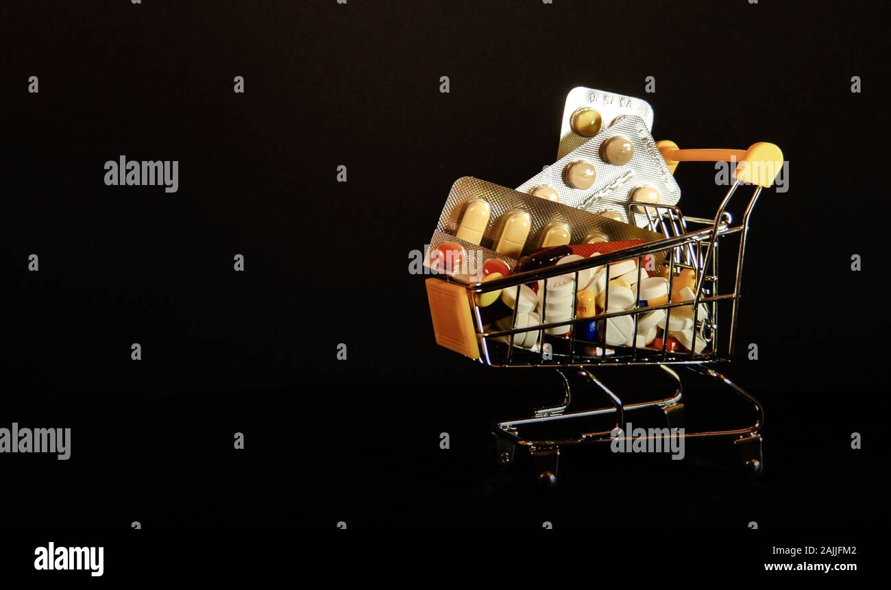Supermarket trolleys filled with medical capsules on black background Stock Photo