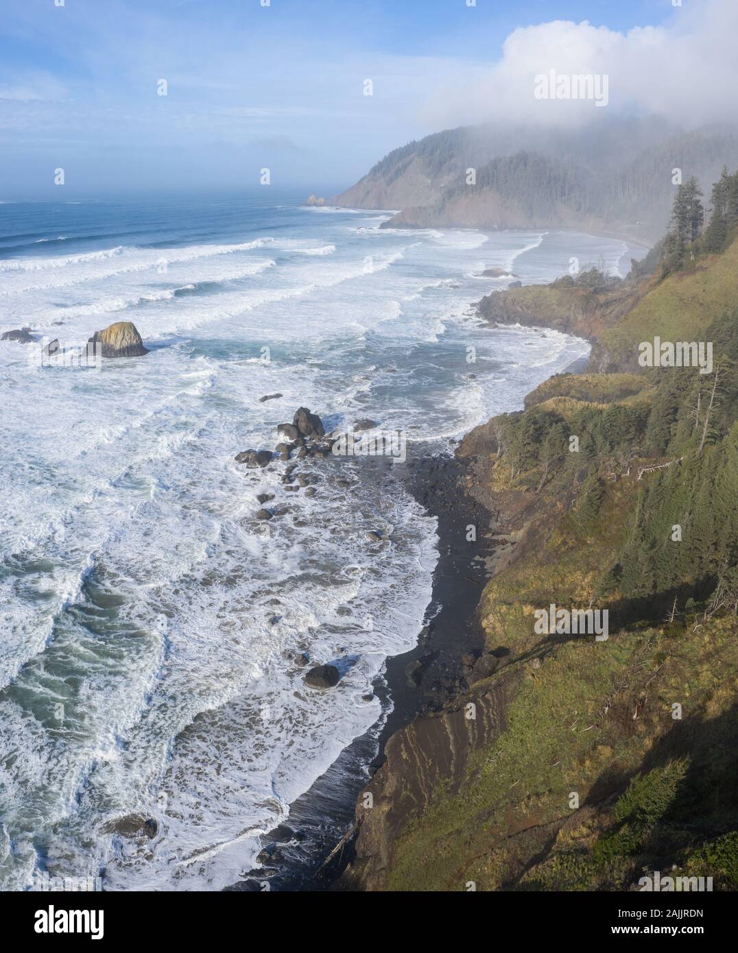 The Pacific Ocean washes against the rocky coastline of northern Oregon. This beautiful, wild region is often covered by a dark foggy marine layer. Stock Photo