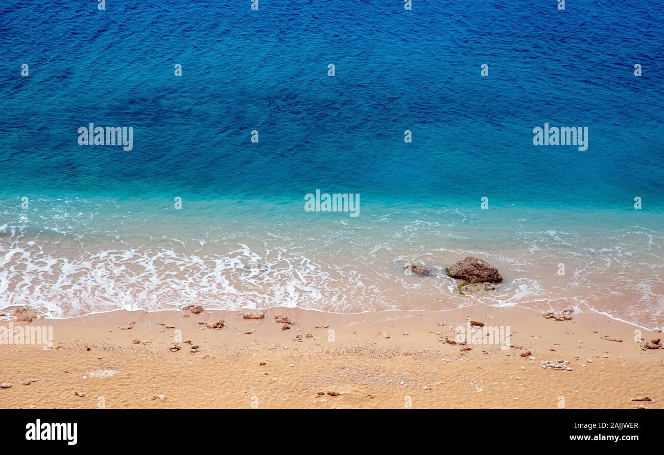 Turquoise colored sea and stones on beach. Stock Photo