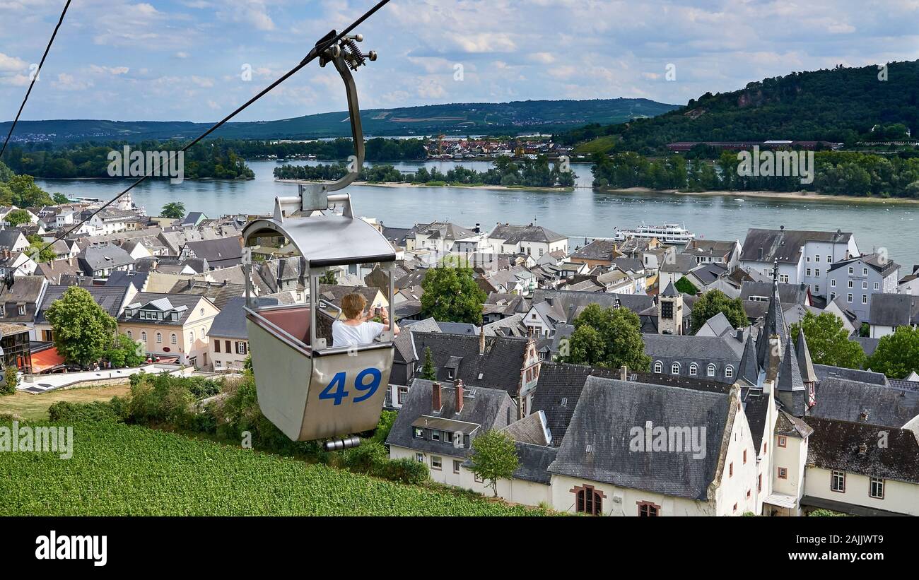 Tourist takes photo from aerial cable car high above the vineyards and medieval town of Rudesheim overlooking the Rhine River. Stock Photo