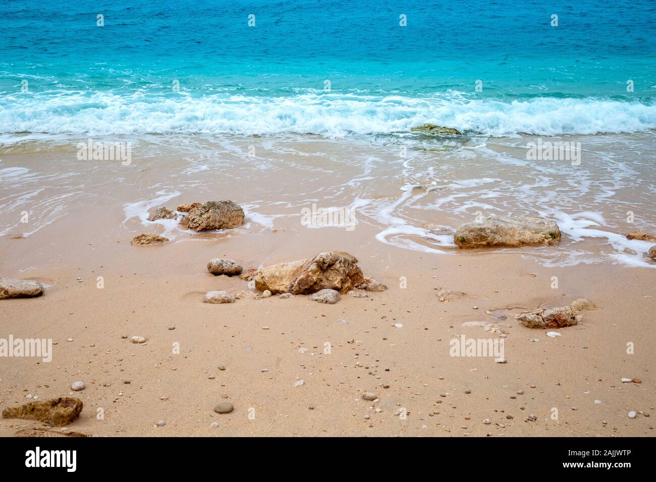 Turquoise colored sea and stones on beach. Stock Photo