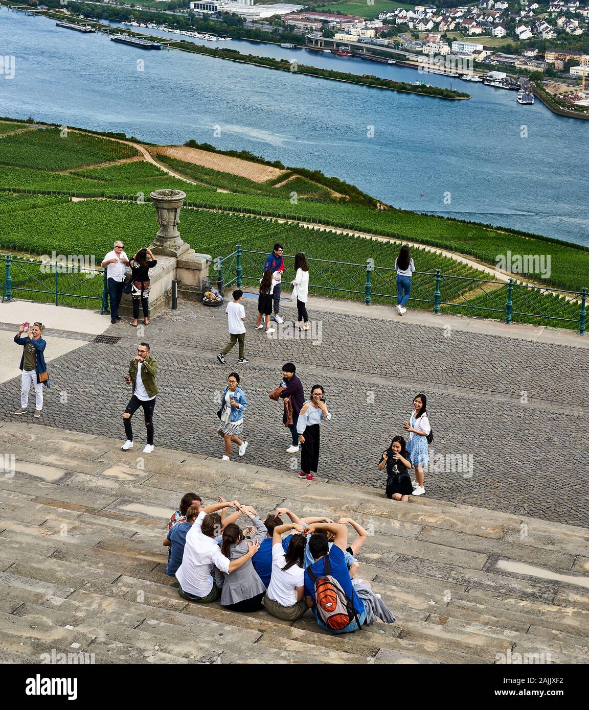 Group of tourists make the heart sign out of their arms at the foot of the Niederwald Memorial high about the Rhine River in Rudesheim, Germany. Stock Photo