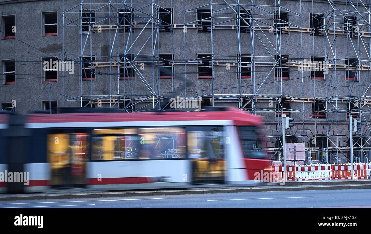 Blurred trolley or tram speeds past a new office complex in the construction phase with scaffolding in Nuremberg, Germany Stock Photo