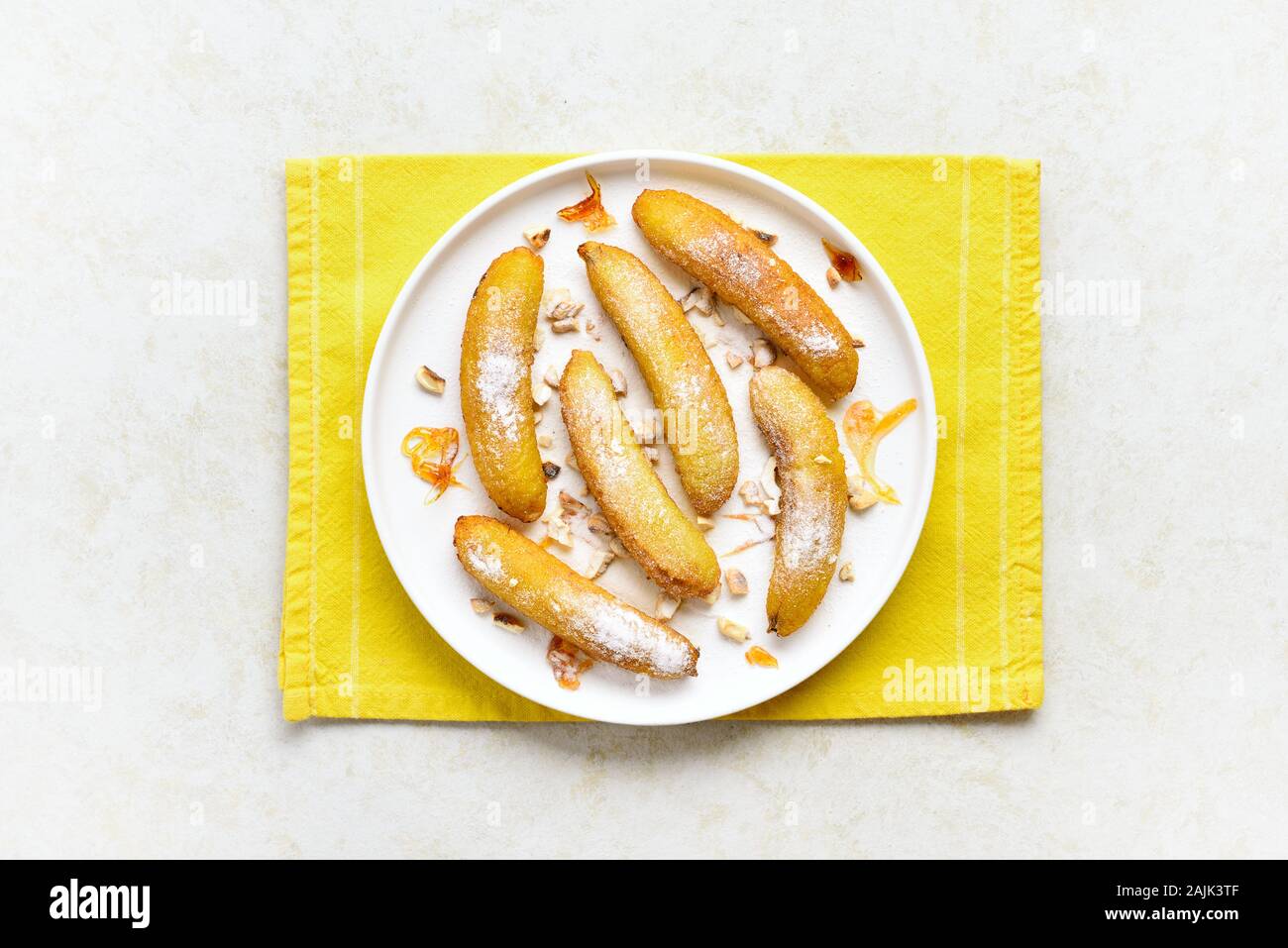 Deep fried bananas on plate over light stone background. Tasty dessert