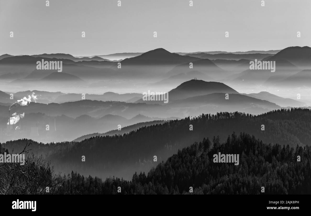 White and black photo. Horizontal landscape photo with hills and valleys.  Šaleška valley, Slovenia, winter afternoon. Represent pollution with smog. Stock Photo