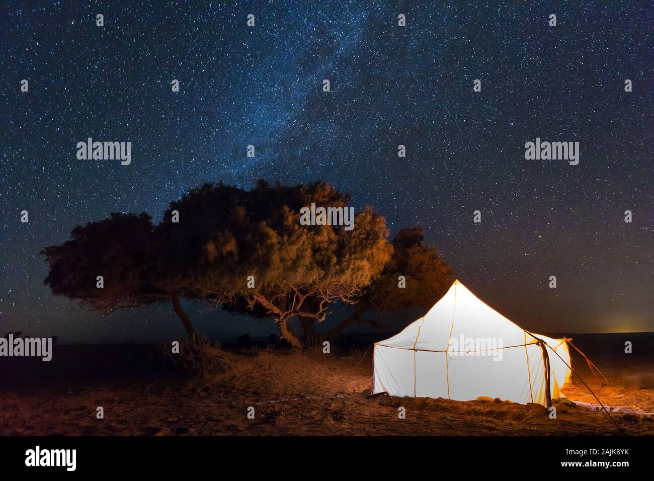 Camp with tent in the desert among sandy dunes. Night with stars in the ...