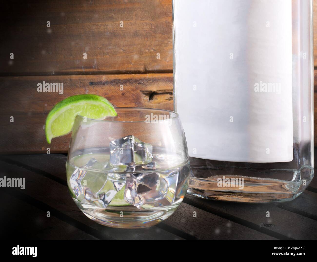 Gin bottle and glass, with ice and a green lime Stock Photo