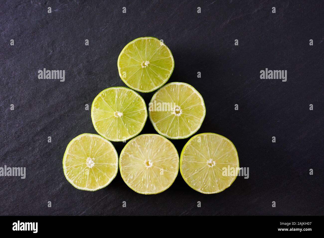 A pyramid of lime halves on black slate ready for use in food or cocktails; copy space Stock Photo