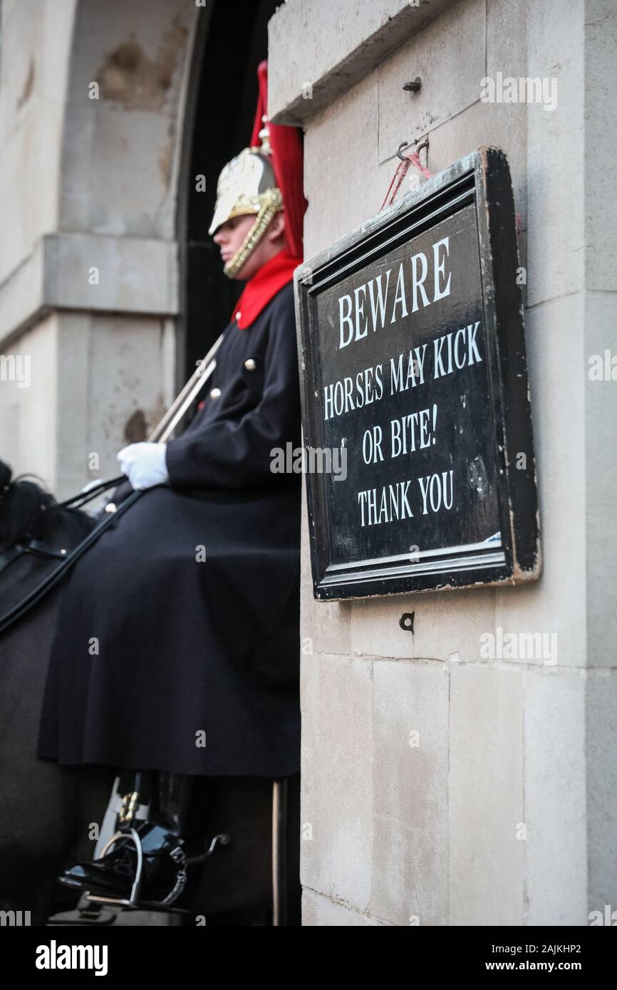 Whitehall Horse Guards, mounted soldier and 'Beware - Horses may kick' sign, Horse Guards Parade, London, UK Stock Photo