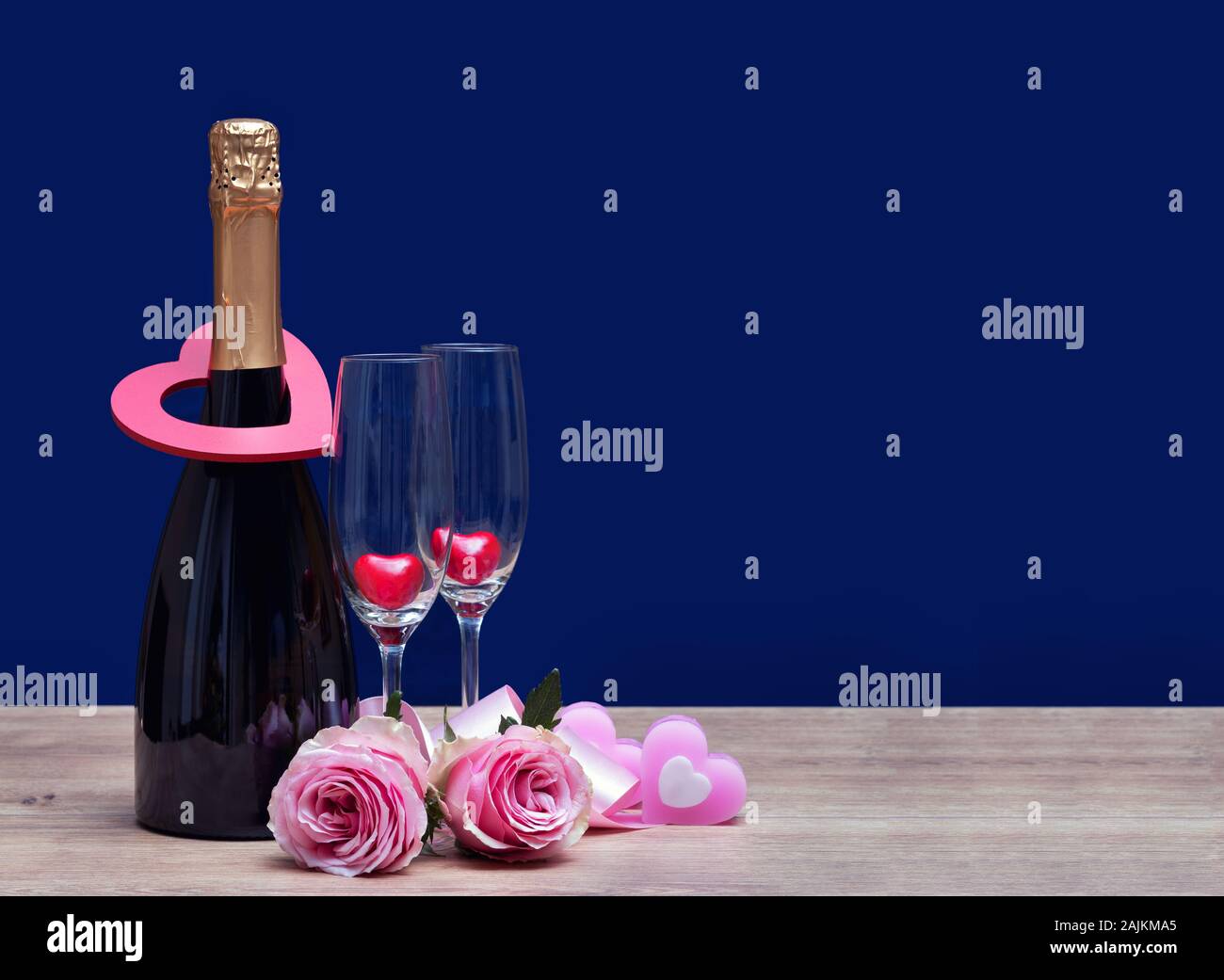 Valentines day background with champagne bottle and two glasses with heart shape two pink roses. International Womens Day March 8 concept. Stock Photo