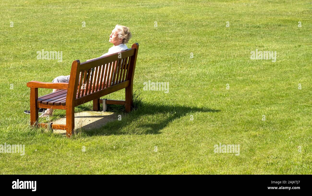 Elderly lady on a park bench enjoying the sunshine Stock Photo - Alamy